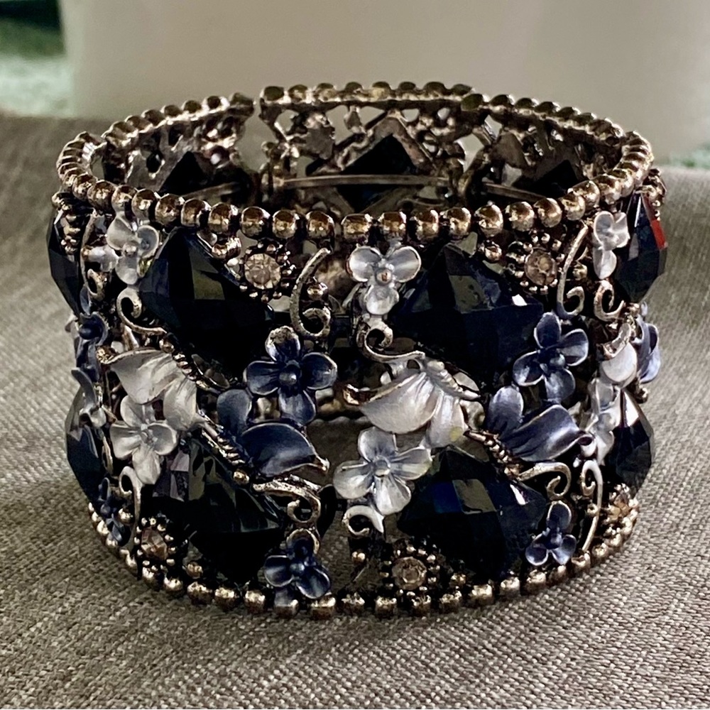 Black bangle cuff with flower motif.